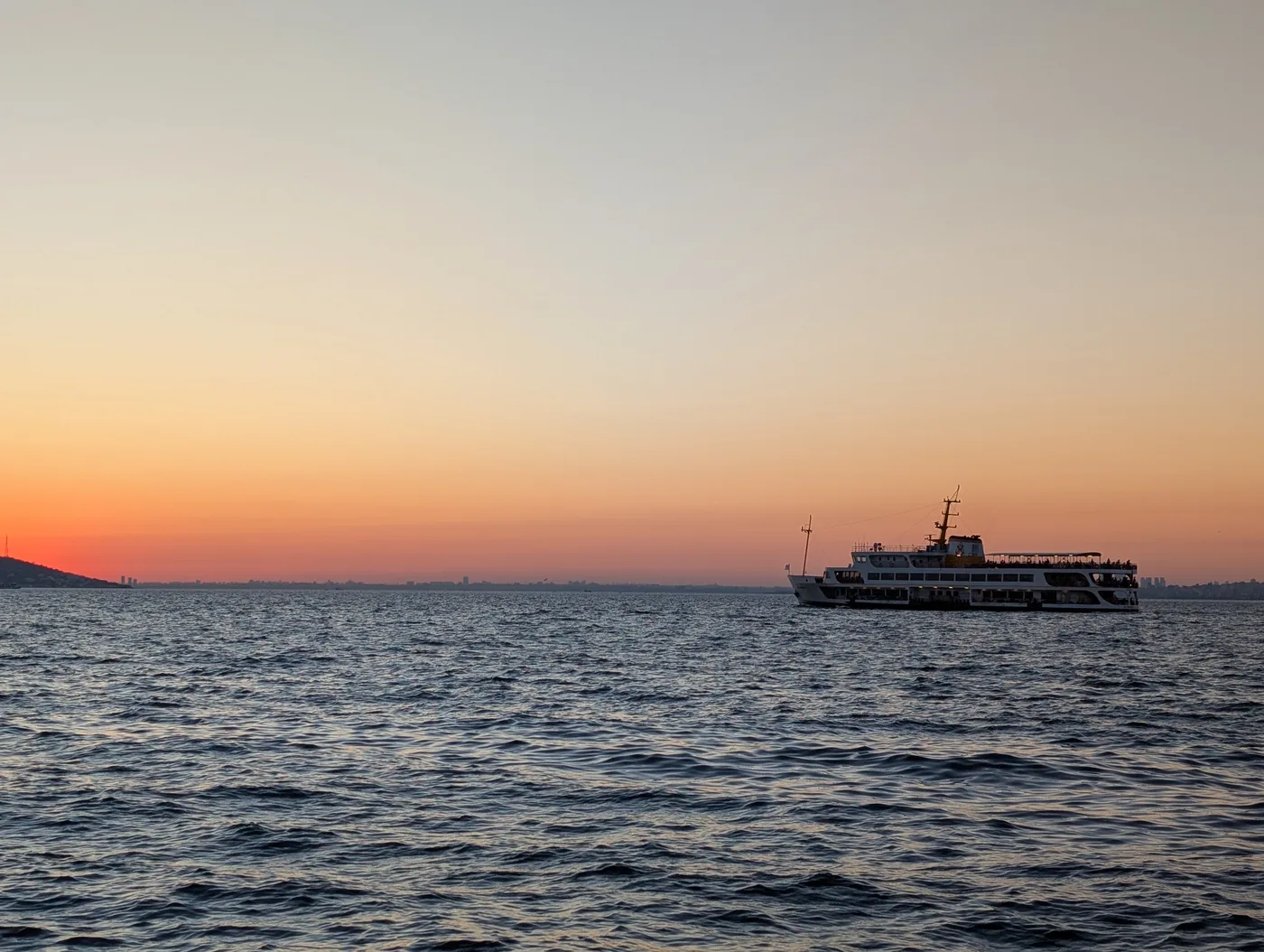 Evening passenger ferry departing Büyükada terminal into twilight